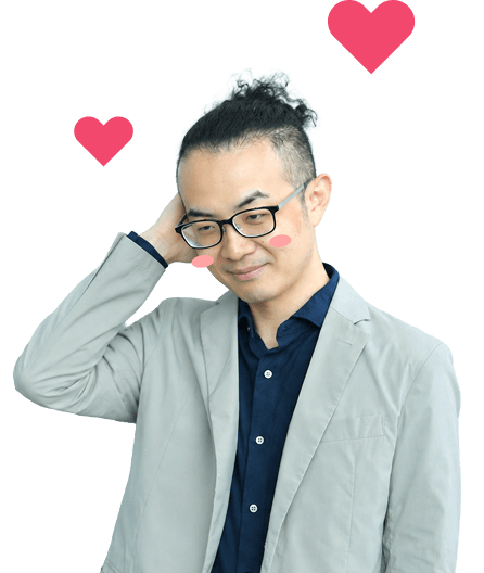 グレーのジャケット姿の眼鏡をかけた男性スタッフが、照れくさそうに頭をかきハートが浮かぶ様子