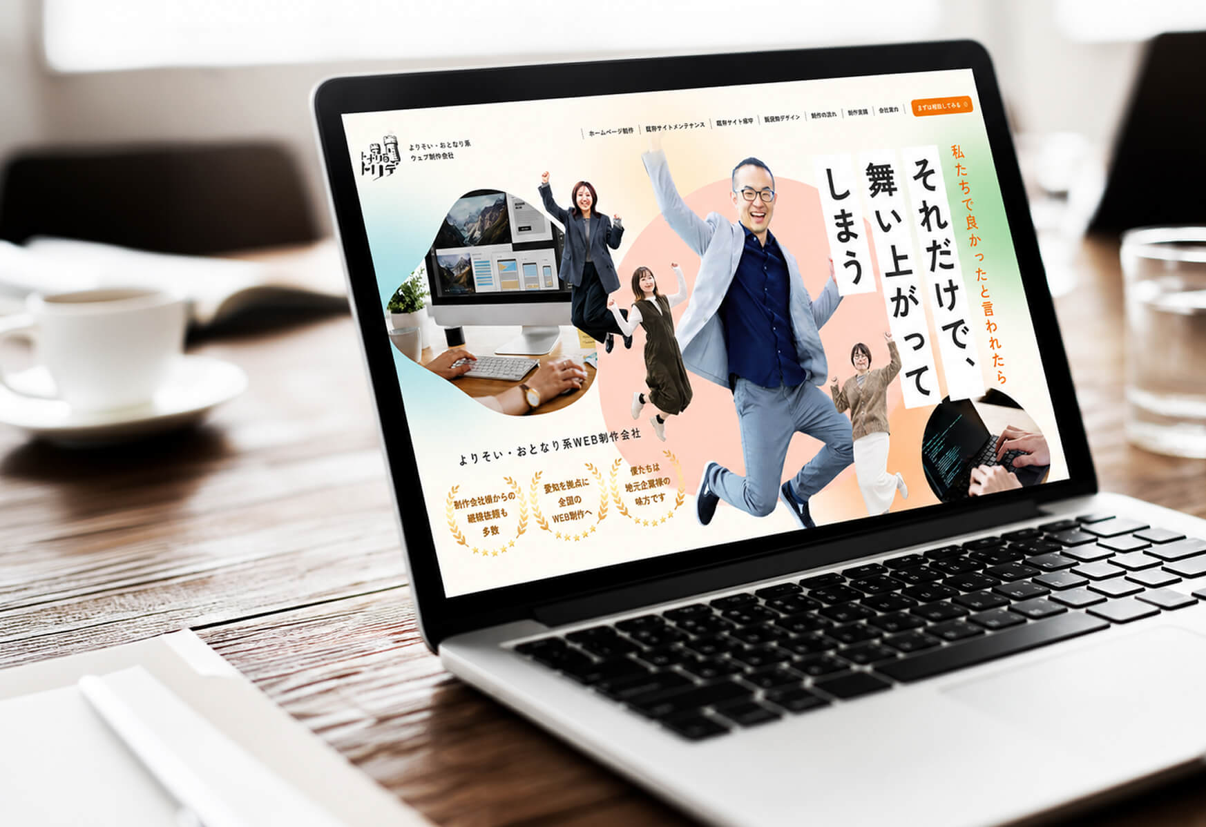 木製テーブルのノートPC画面に、笑顔で腕を広げるスタッフが写ったWEBサイトが表示されている様子