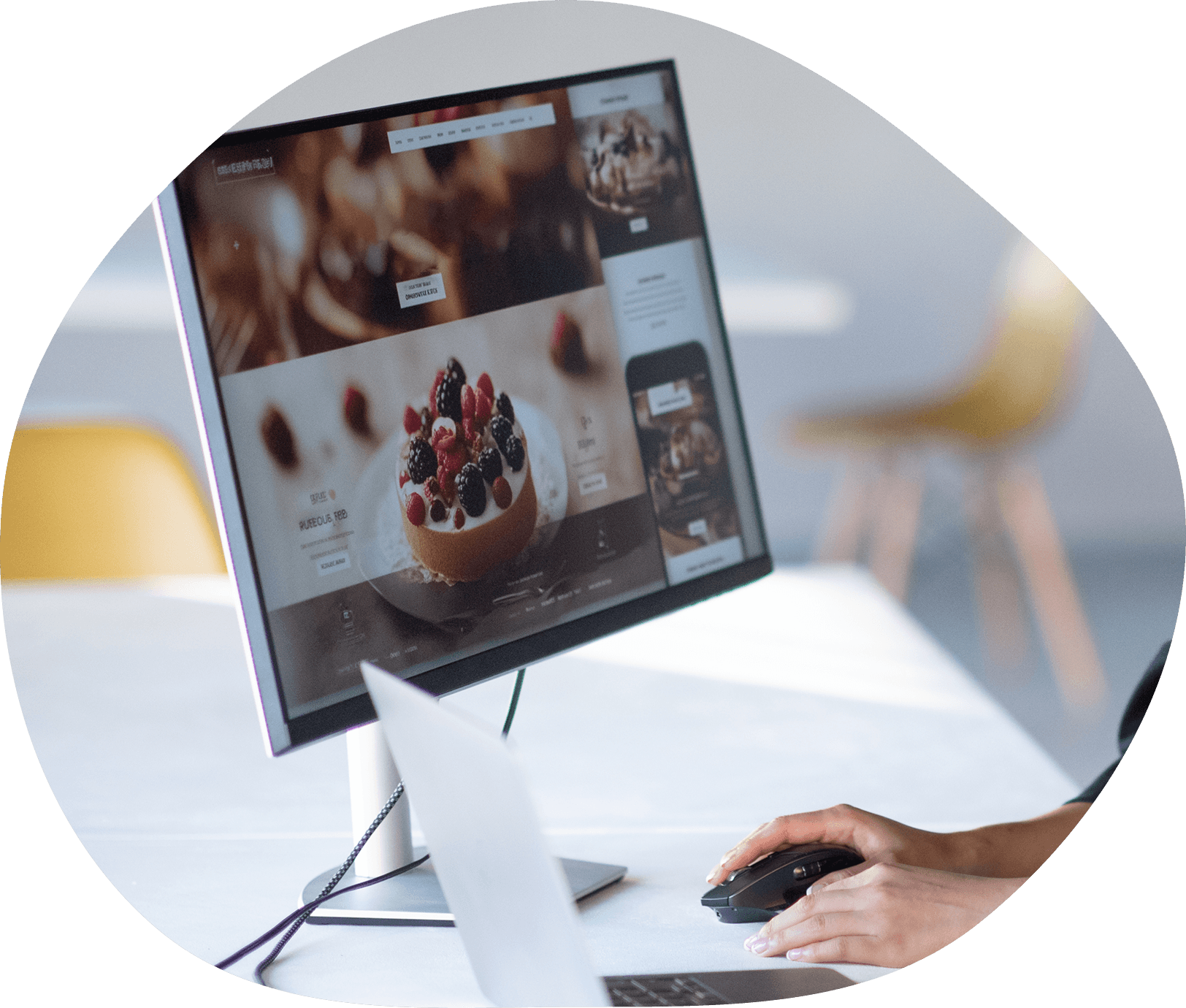 白いデスクの上にディスプレイがあり、マウスを手に制作をしている様子