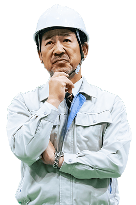 作業着姿のヘルメットをつけた男性が、手を顎にあてて悩んでいる様子